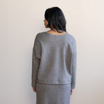 Woman showing the back wearing a grey sweater