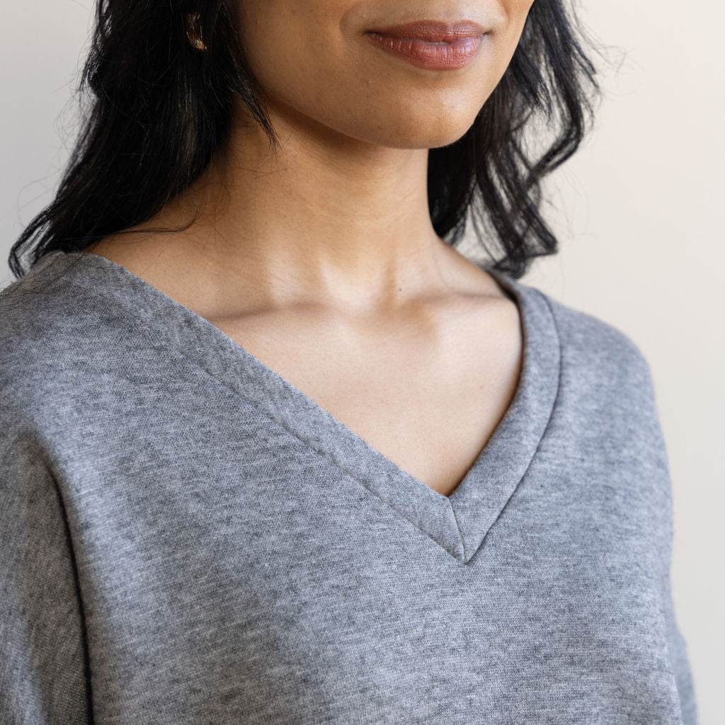 Close up on the neckline of a grey v-neck sweater