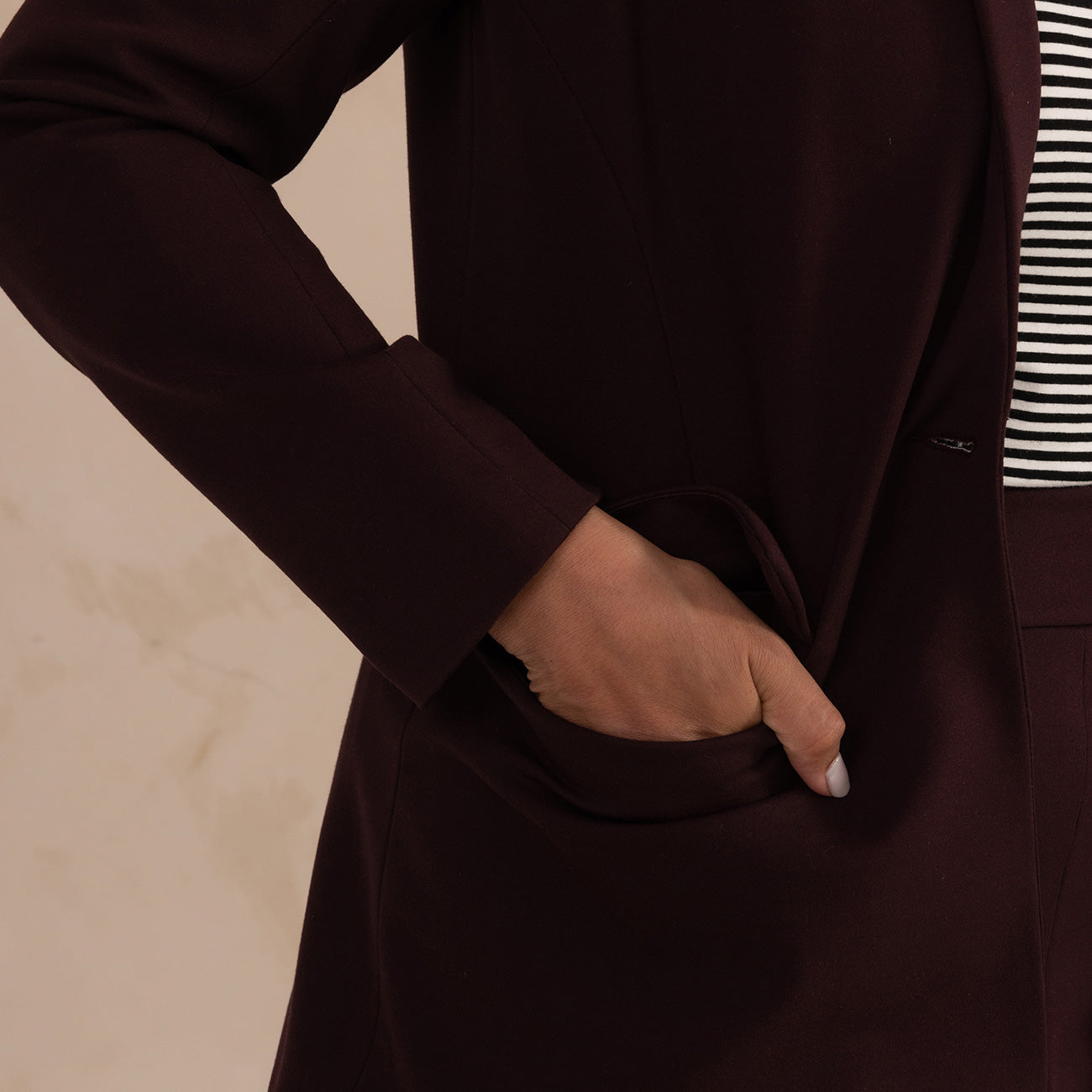 woman putting her hand on the pocket of an aubergine blazer