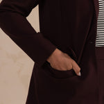 woman putting her hand on the pocket of an aubergine blazer