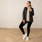 woman wearing a grey blazer on top of a sand coloured hoodie paired with black leggings and white sneakers