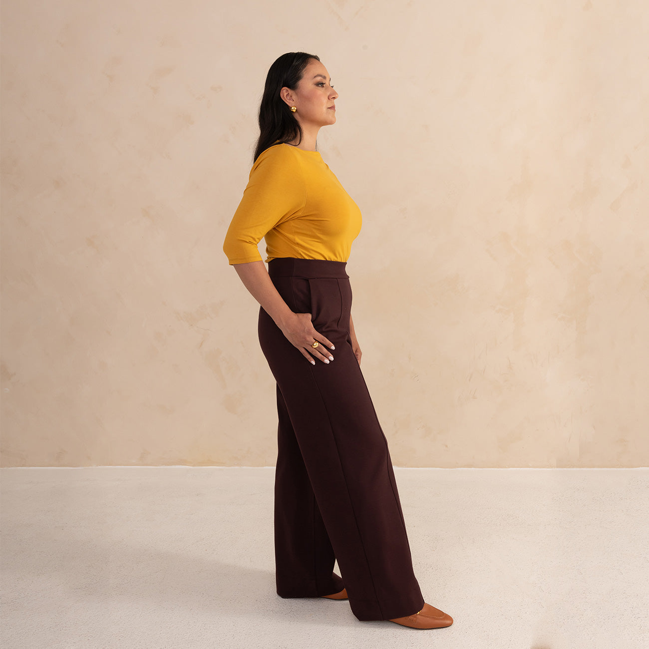 woman wearing a yellow 3/4 sleeve length and aubergine high waisted wide leg pants