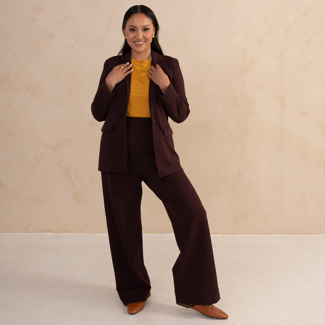 woman wearing a matching suit in aubergine, paired with a yellow boat neck
