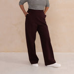 woman wearing a 3/4 sleeve stripes boat neck top paired with aubergine high waisted wide leg trouser pants