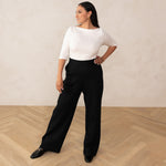 woman wearing a white 3/4 sleeve length and black high waisted wide leg pants