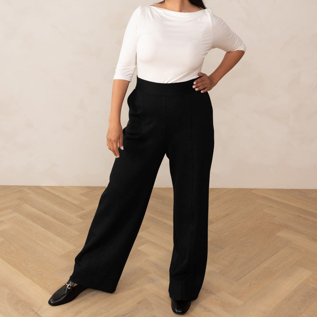 woman wearing a white 3/4 sleeve length and black high waisted wide leg pants