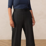 woman wearing a navy boat neck top paired with grey high waisted wide leg trouser pants