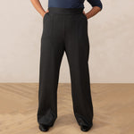 woman wearing a navy boat neck top paired with grey high waisted wide leg trouser pants