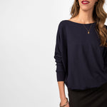 Woman wearing loose navy blue scoop neckline sweatshirt with black skirt