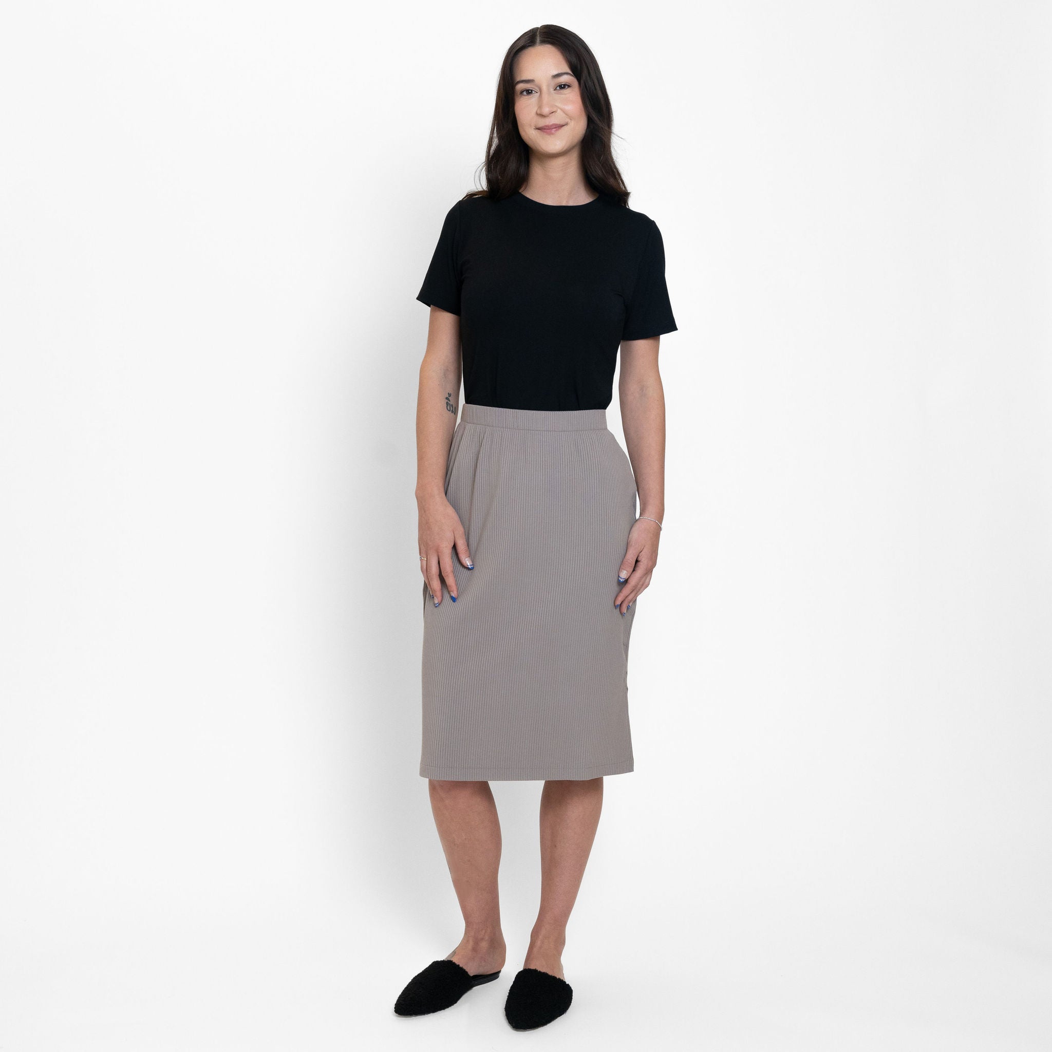 Woman wearing loose black crew neck t-shirt with beige knee length skirt