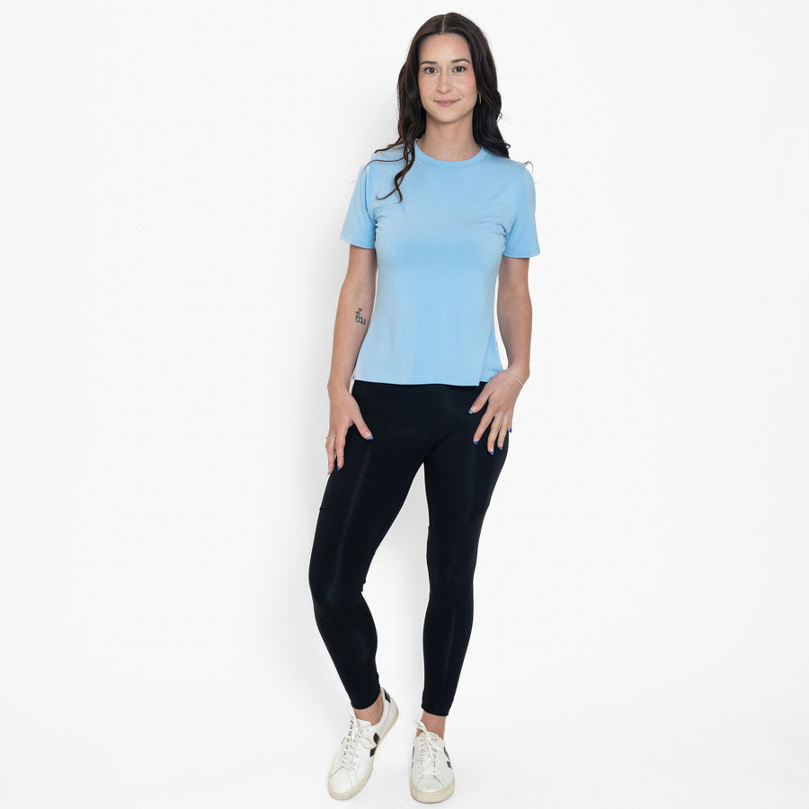 Woman wearing loose light blue crew neck t-shirt with black fitted leggings