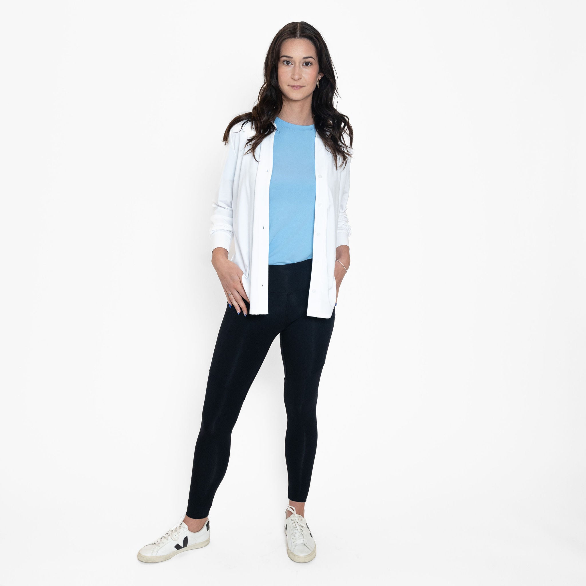 Woman wearing loose light blue crew neck t-shirt with black fitted leggings and white open button up long sleeve shirt