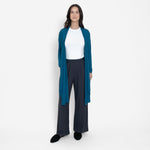 Woman wearing loose white crew neck t-shirt and loose black stretchy wide leg pants with bright blue cardigan