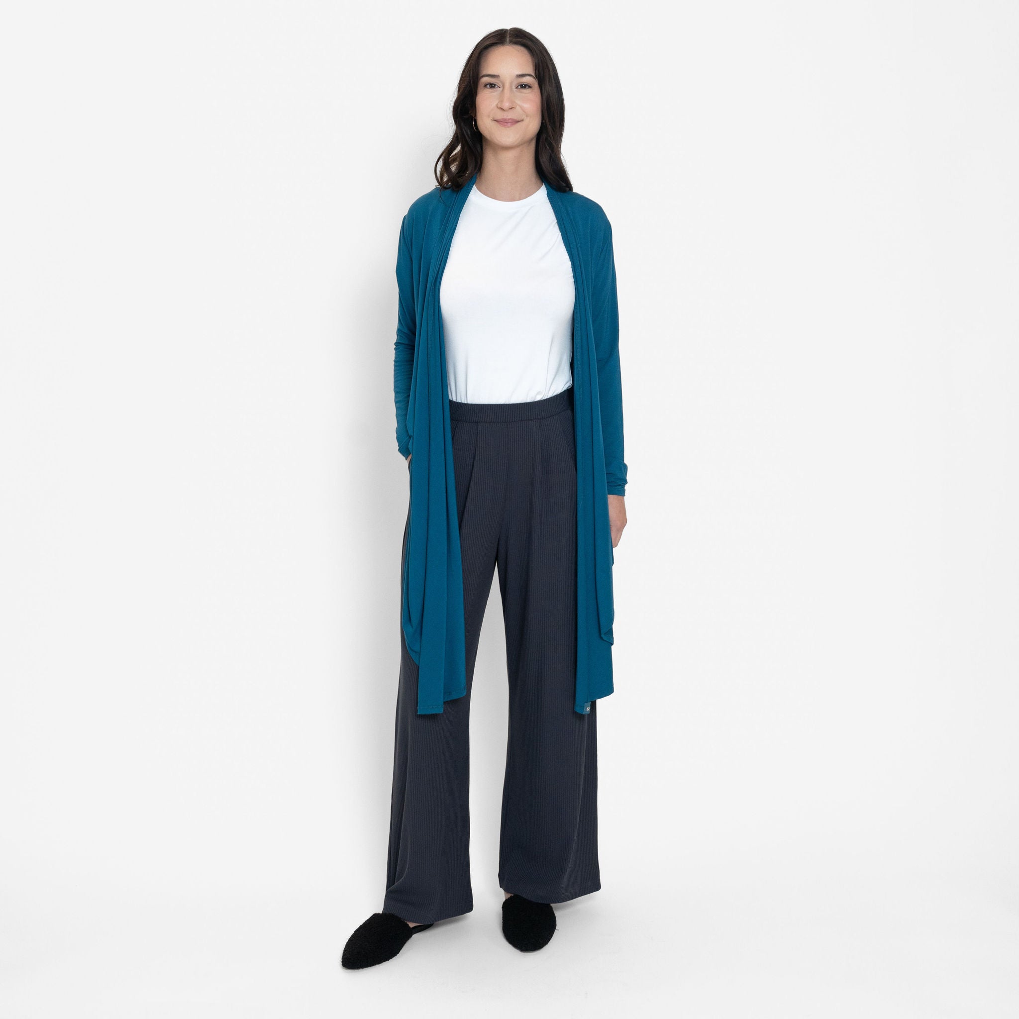 Woman wearing loose white crew neck t-shirt and loose black stretchy wide leg pants with bright blue cardigan