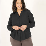 Woman wearing black long sleeve button up shirt with brown fitted leggings