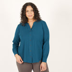 Woman wearing teal long sleeve button up shirt with brown fitted leggings