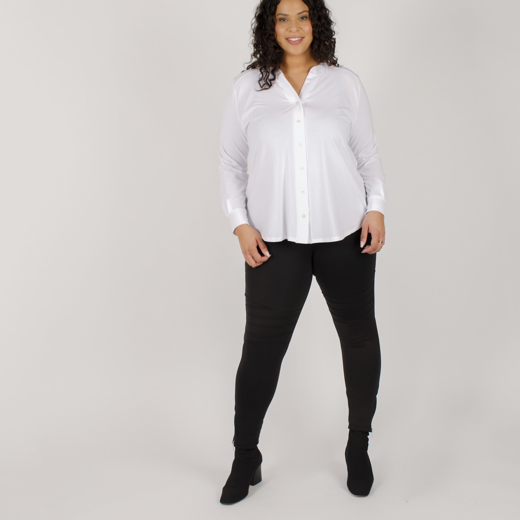 Woman wearing fitted black high-rise waist with ankle length leggings featuring seamless stitching and a hidden back pocket with white button up shirt
