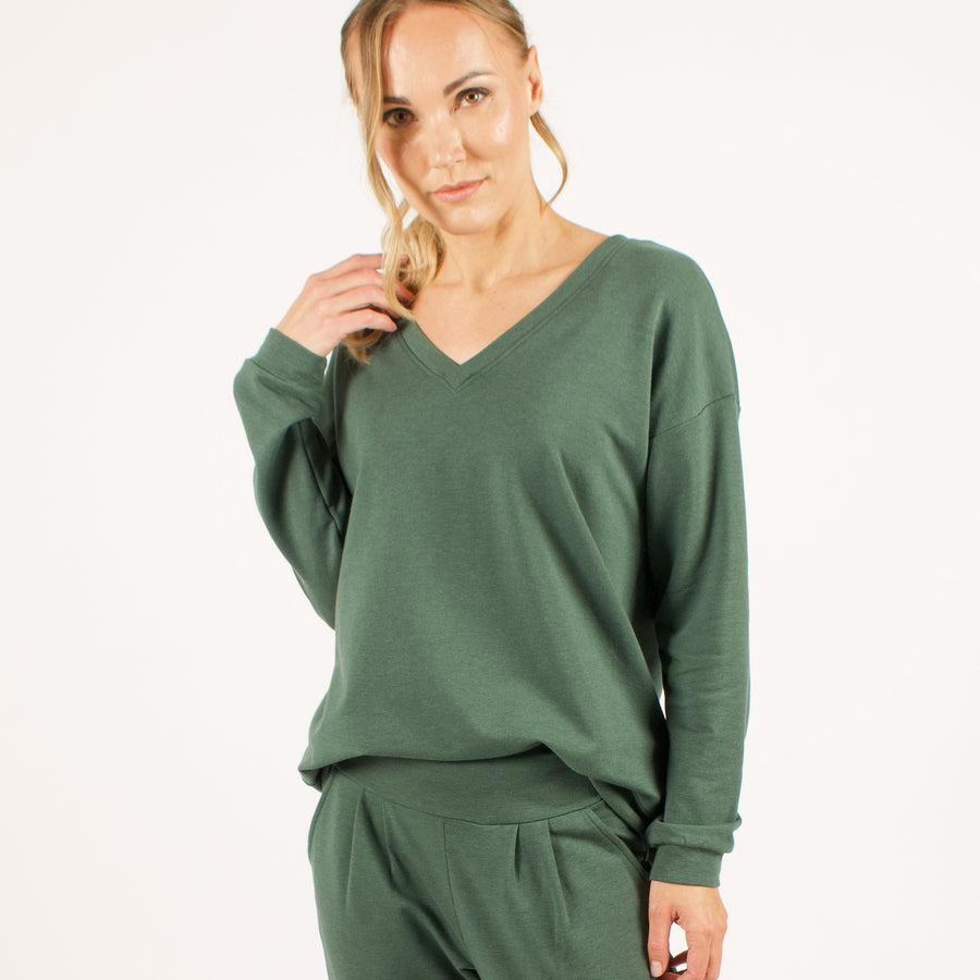 Woman wearing reversible green v-neckline loose sweatshirt with matching green sweatpants