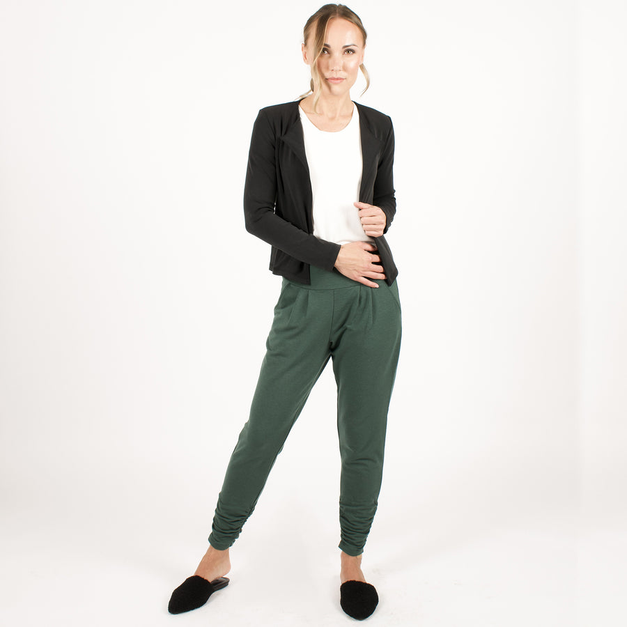 Woman wearing dark green stretchy sweatpants with white shirt and black cardigan 