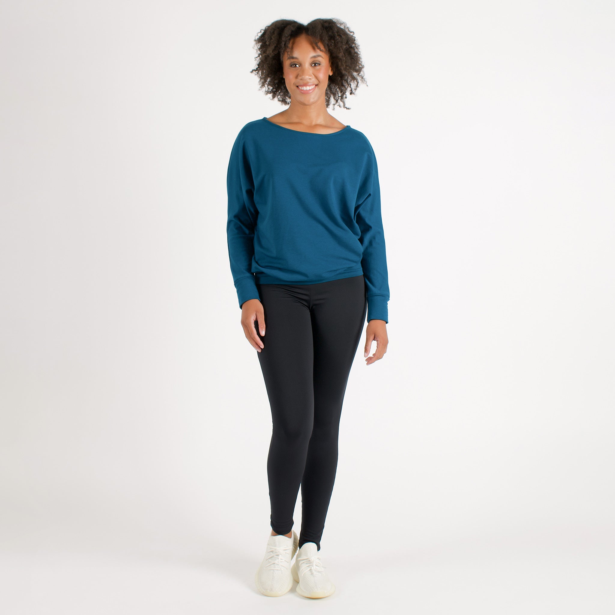 Woman wearing fitted black high-rise waist with ankle length leggings featuring seamless stitching and a hidden back pocket with bright blue sweatshirt