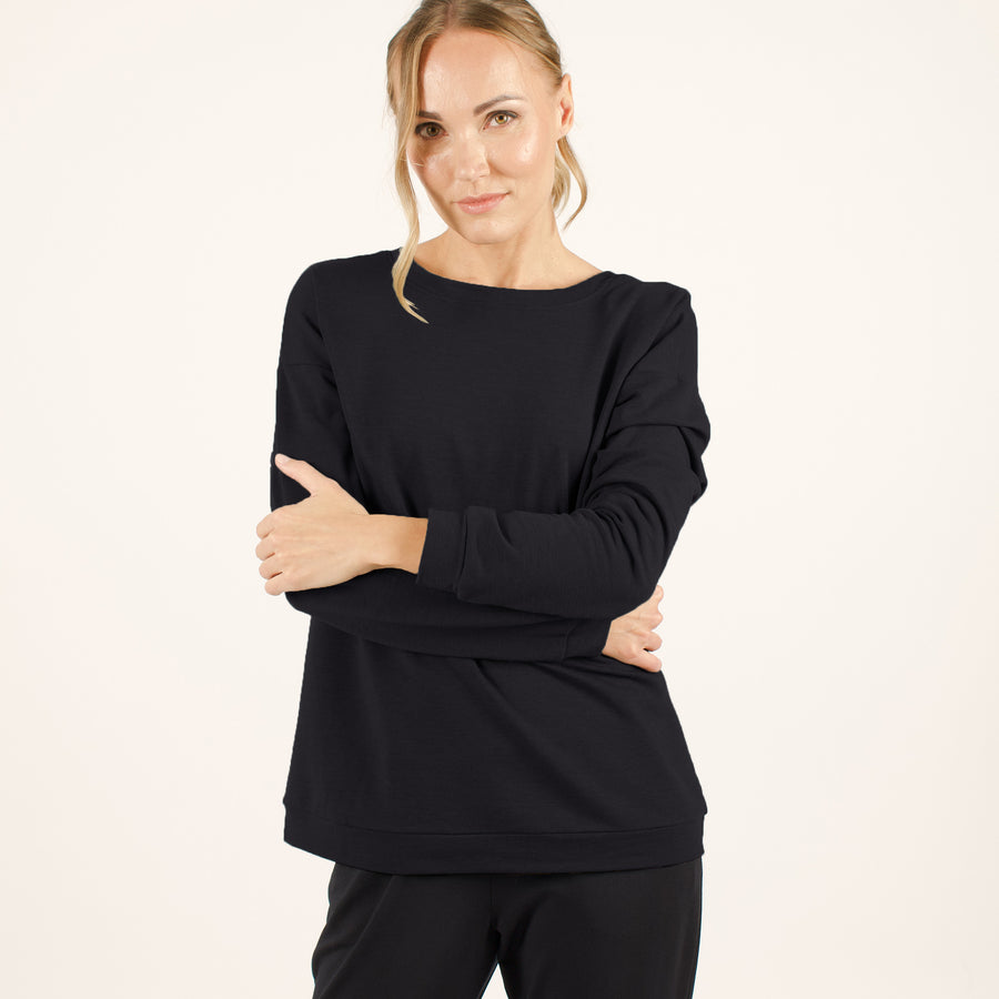 Woman wearing reversible black v-neckline loose sweatshirt with matching black sweatpants