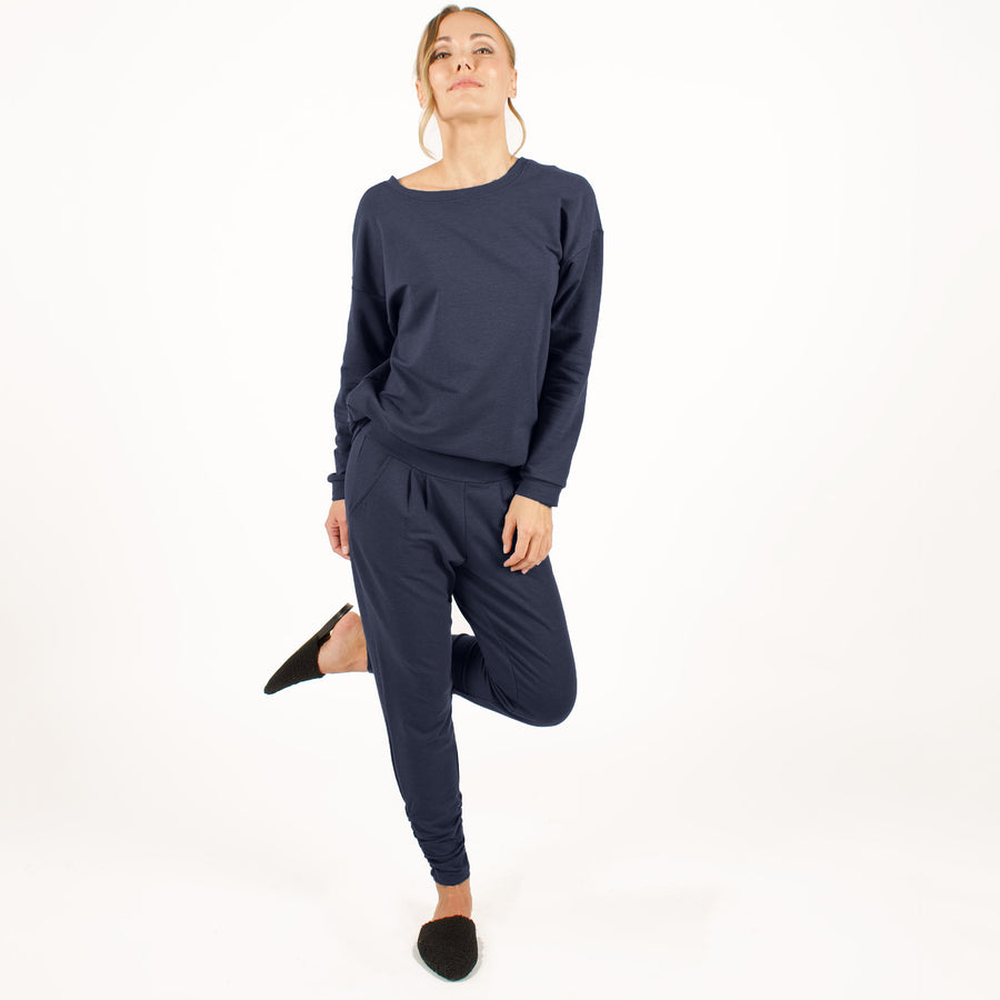 Woman wearing reversible navy blue v-neckline loose sweatshirt with matching navy blue sweatpants