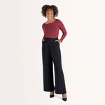 Woman wearing cherry red form fitting long sleeve reversible top with either a scoop neckline or horizontal neckline paired with black wide leg pant