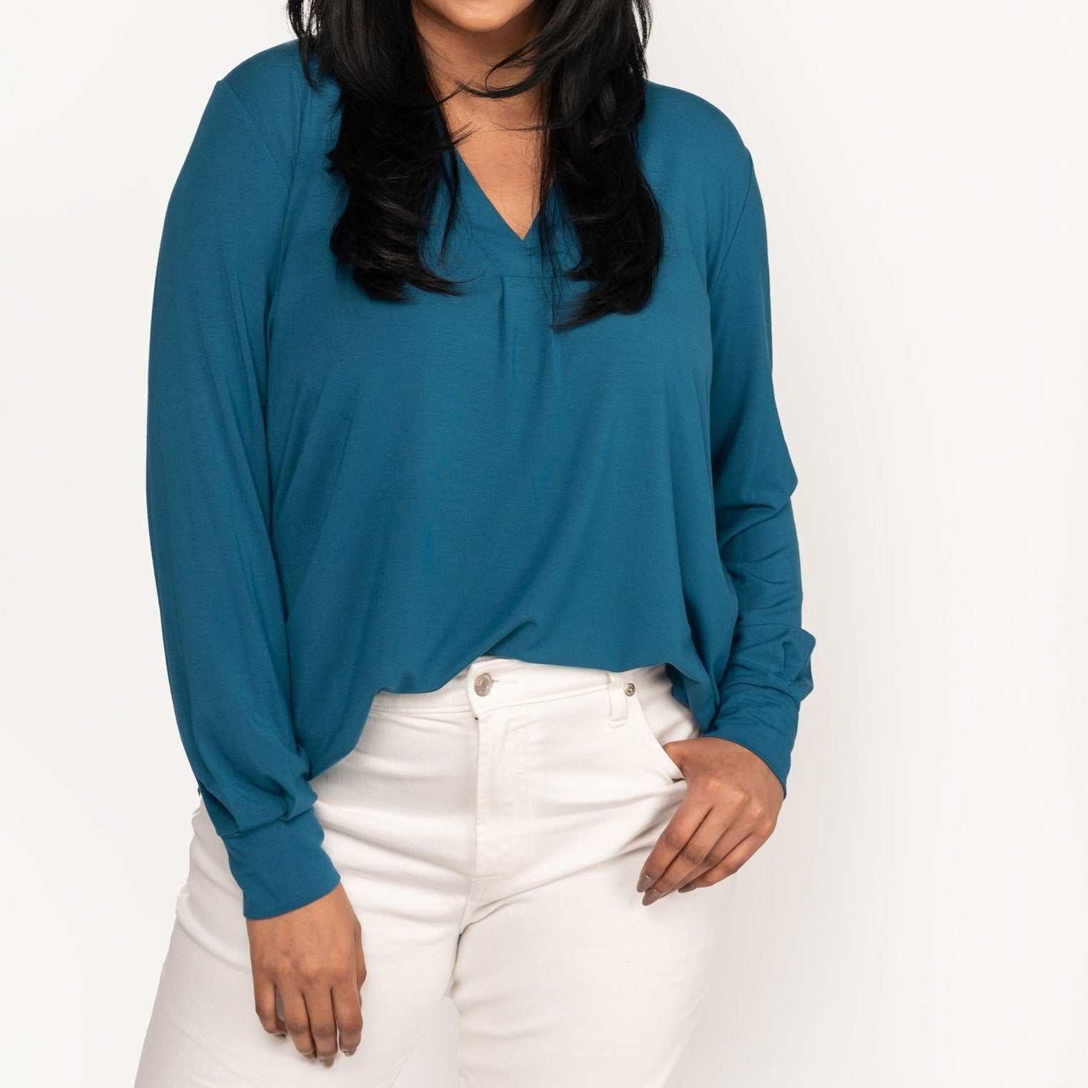 Woman wearing a loose flowing blue v-neckline shirt with white jeans
