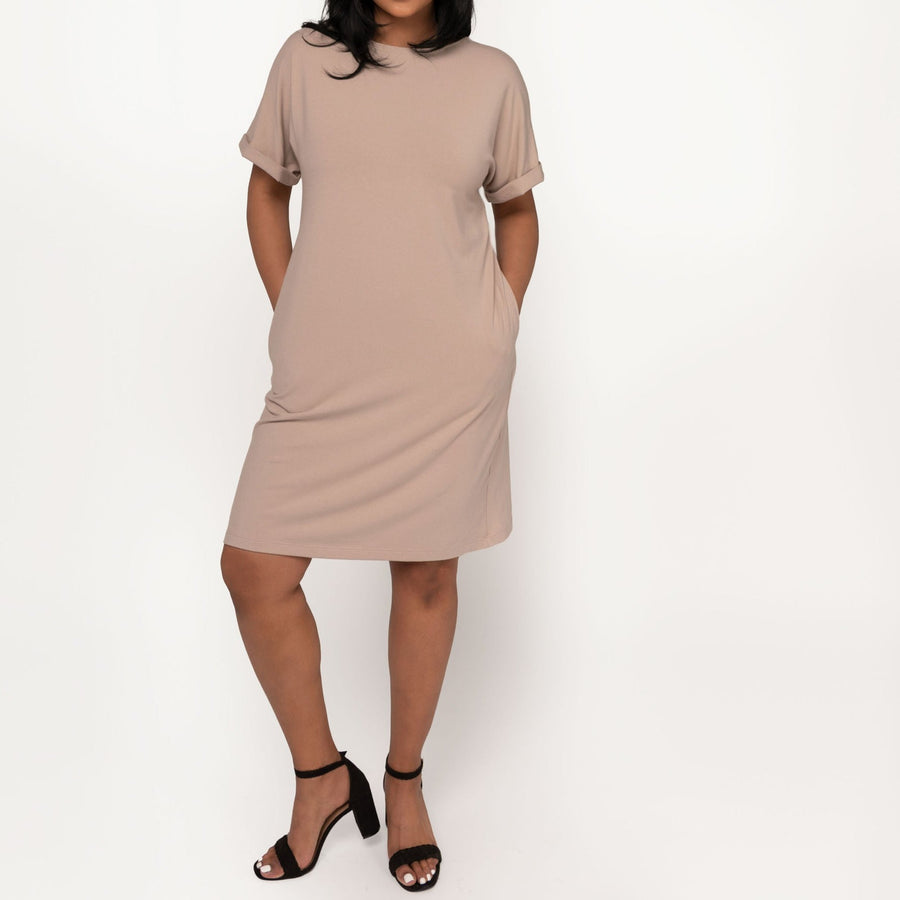 Woman wearing loose beige short sleeve knee length dress with pockets