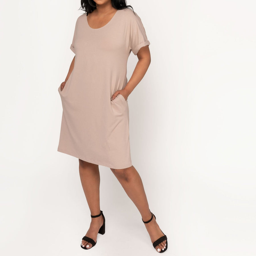 Woman wearing loose beige short sleeve knee length dress with pockets
