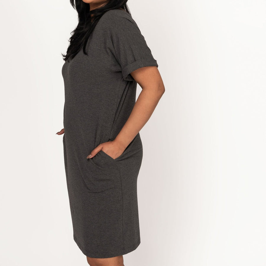 Woman wearing loose dark grey short sleeve knee length dress with pockets