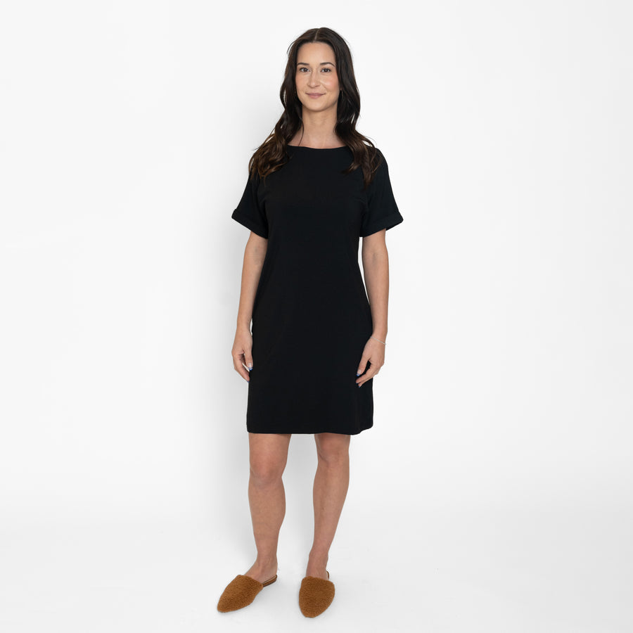 Woman wearing loose black short sleeve knee length dress with pockets
