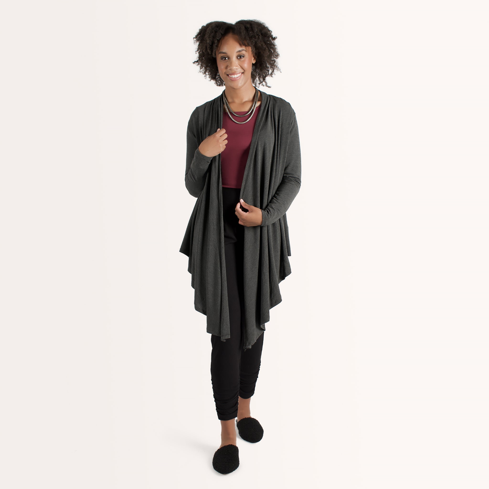 Woman wearing long sleeve dark grey cardigan with red scoop neckline shirt and black fitted pants