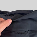 Woman wearing fitted black high-rise waist with ankle length leggings featuring seamless stitching and a hidden back pocket 