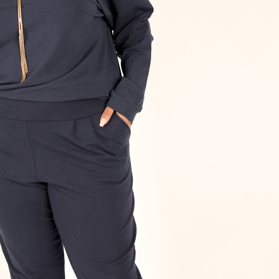 Woman wearing navy stretchy sweatpants with pockets and matching blue loose fitted sweatshirt