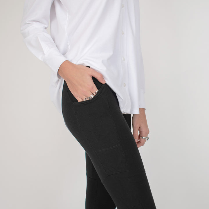 Woman wearing black form fitting stretchy leggings with hip pocket with white button up shirt