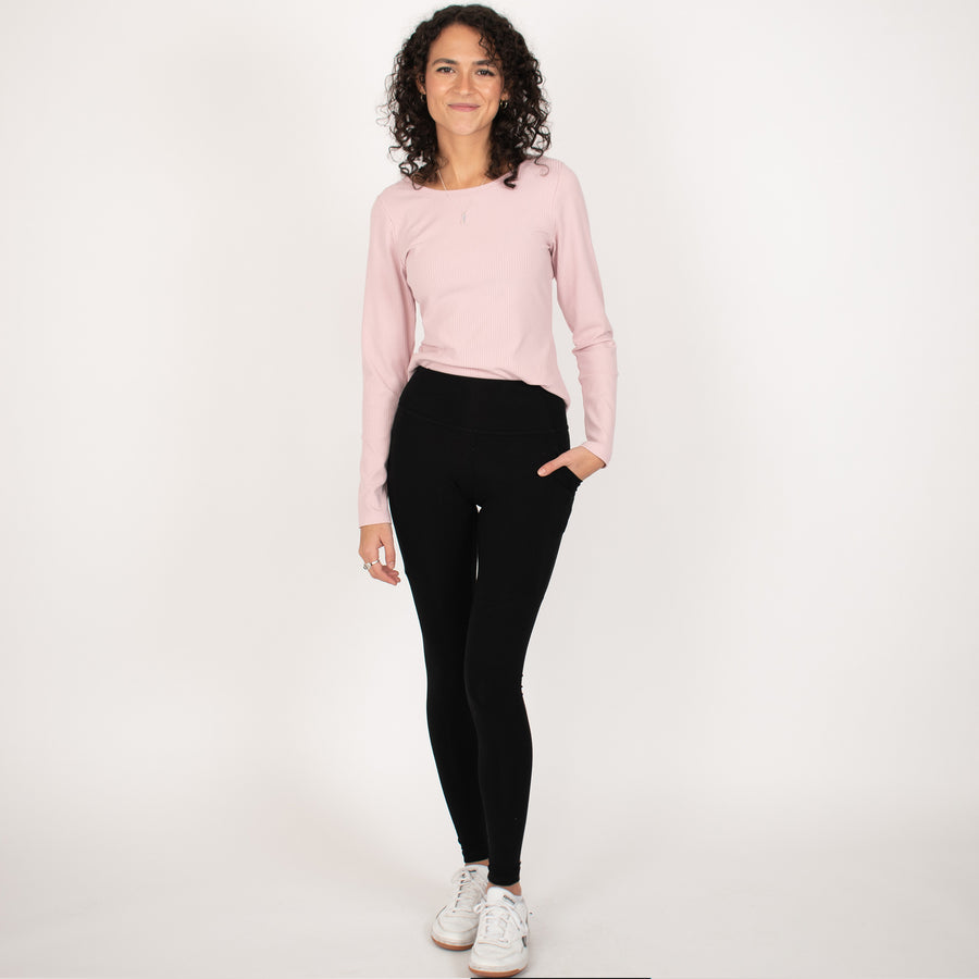 Woman wearing light pink rib knit reversible long sleeve top with black tapered leggings