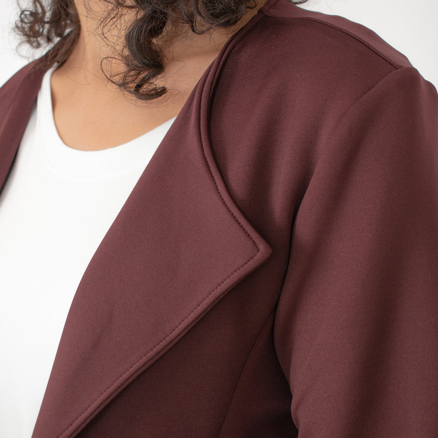 Woman wearing a burnt red jacket with lapels in a moto-inspired silhouette with invisible pockets with white t-shirt