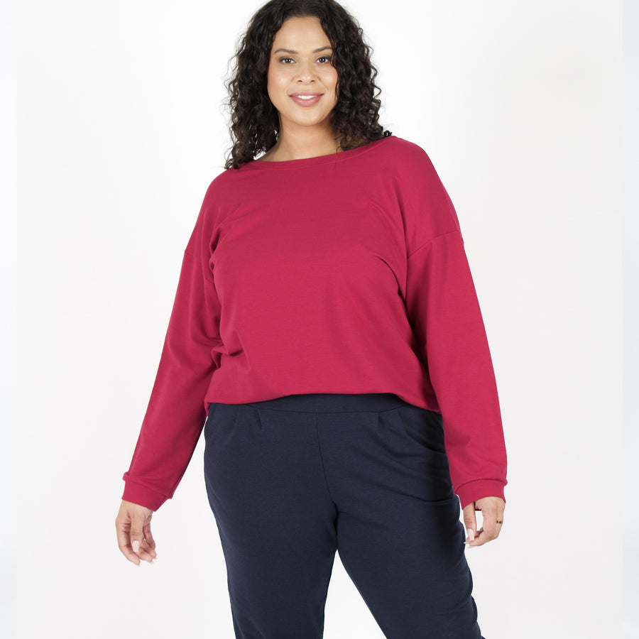 Woman wearing reversible red v-neckline loose sweatshirt with navy blue fitted sweatpants