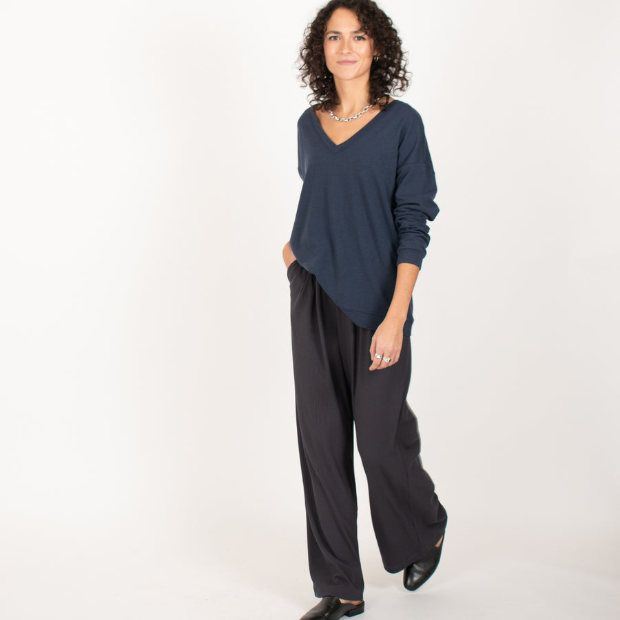Woman wearing reversible navy blue v-neckline loose sweatshirt with stretchy wide leg pants