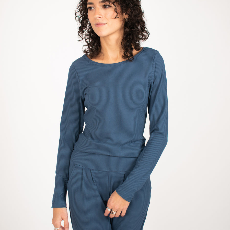 Woman wearing blue rib knit reversible long sleeve top with matching blue fitted sweatpants 