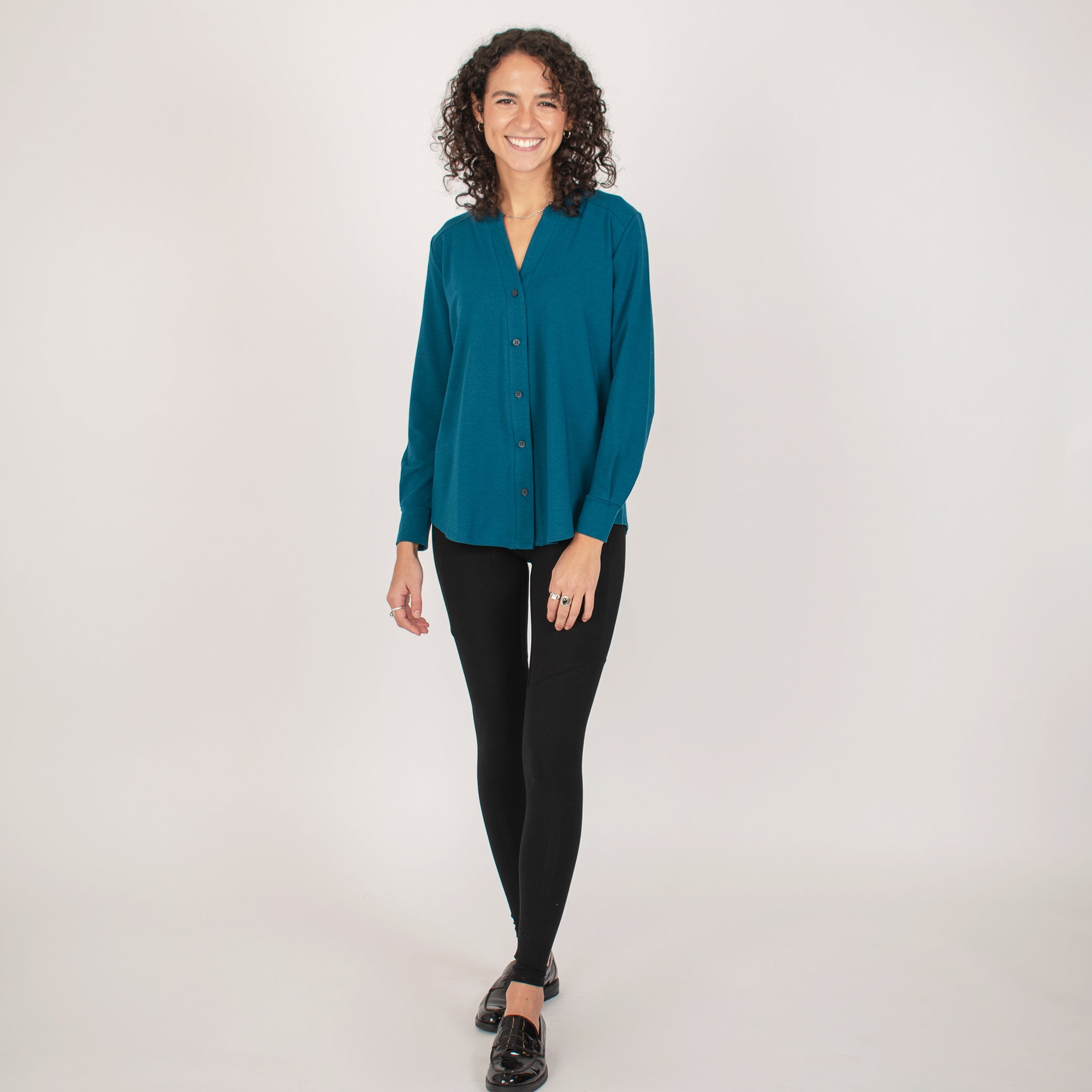 Woman wearing bright blue long sleeve button up shirt with black leggings