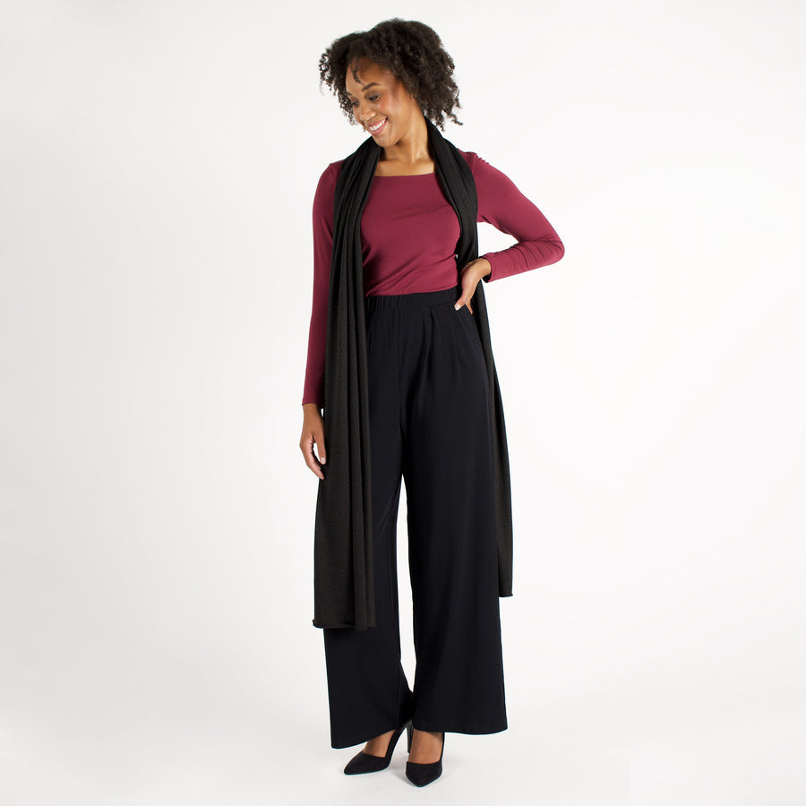 Woman wearing wrap-up scarf around their neck with maroon long sleeve shirt and black flowing pants