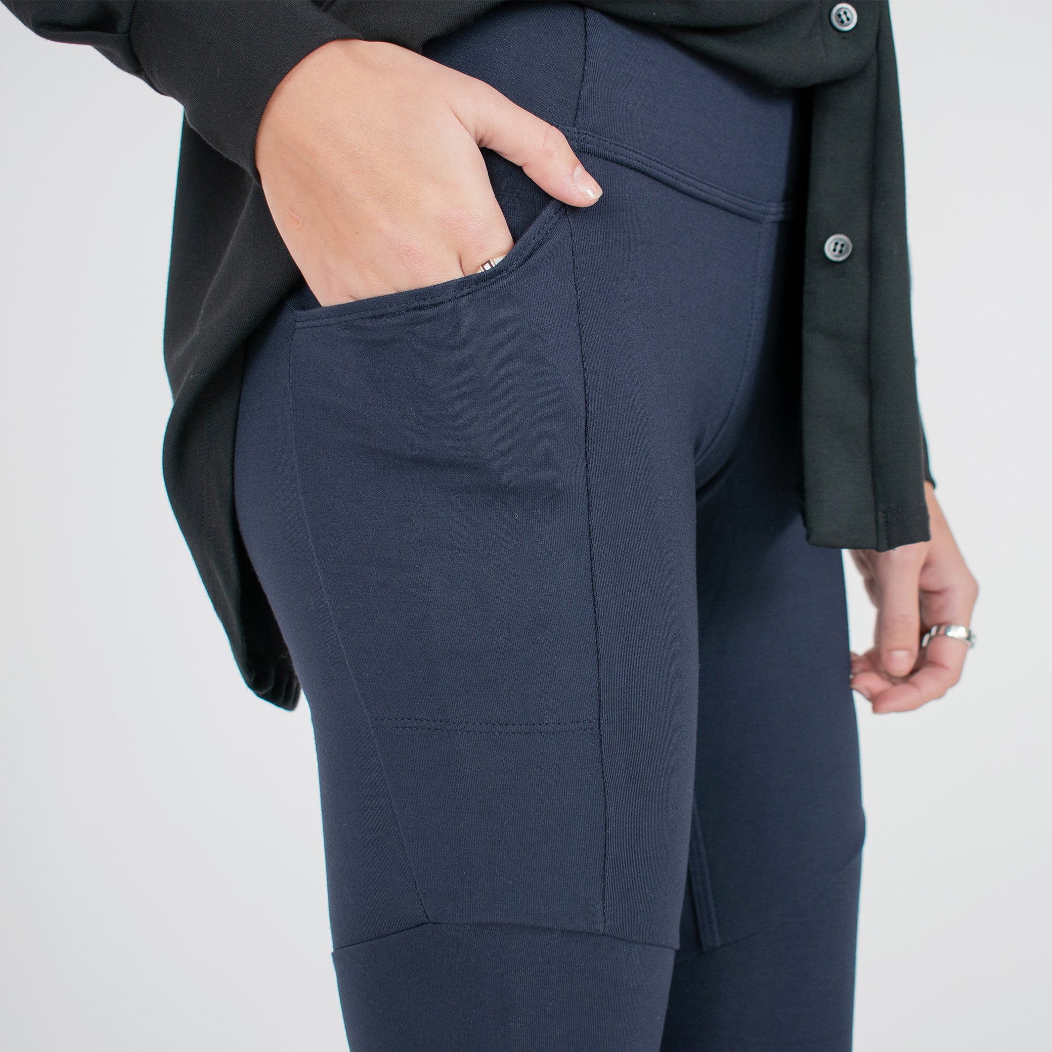 Woman wearing navy blue form fitting stretchy leggings with hip pocket with black button up shirt