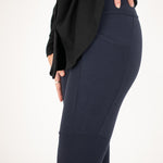 Woman wearing navy blue form fitting stretchy leggings with hip pocket with black shirt