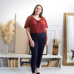 Woman wearing navy blue vertical ribbed stretchy band sweatpants with a red cowl neck blouse