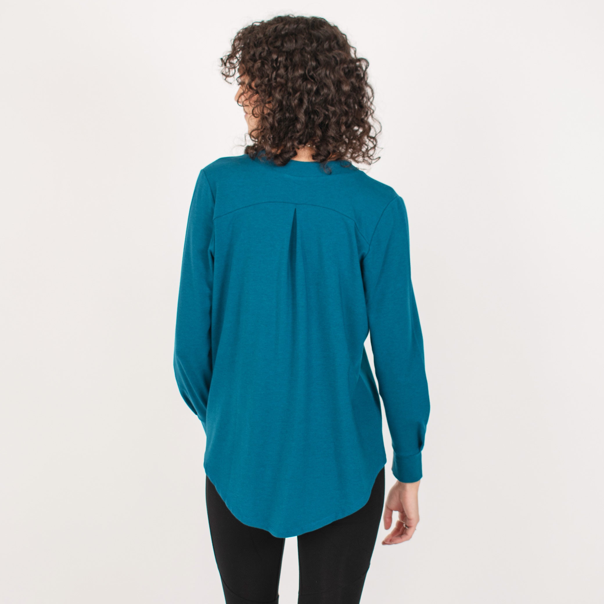 Woman wearing bright blue long sleeve button up shirt with black leggings