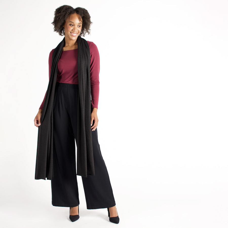 Woman wearing wrap-up scarf around their neck with maroon long sleeve shirt and black flowing pants
