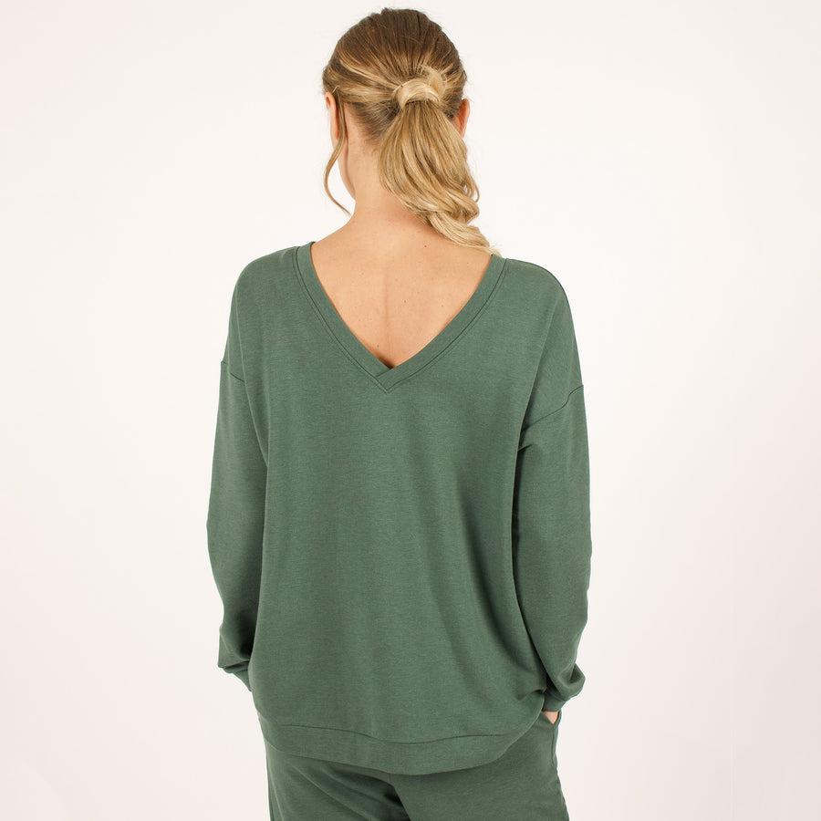 Woman wearing reversible green v-neckline loose sweatshirt with matching green sweatpants