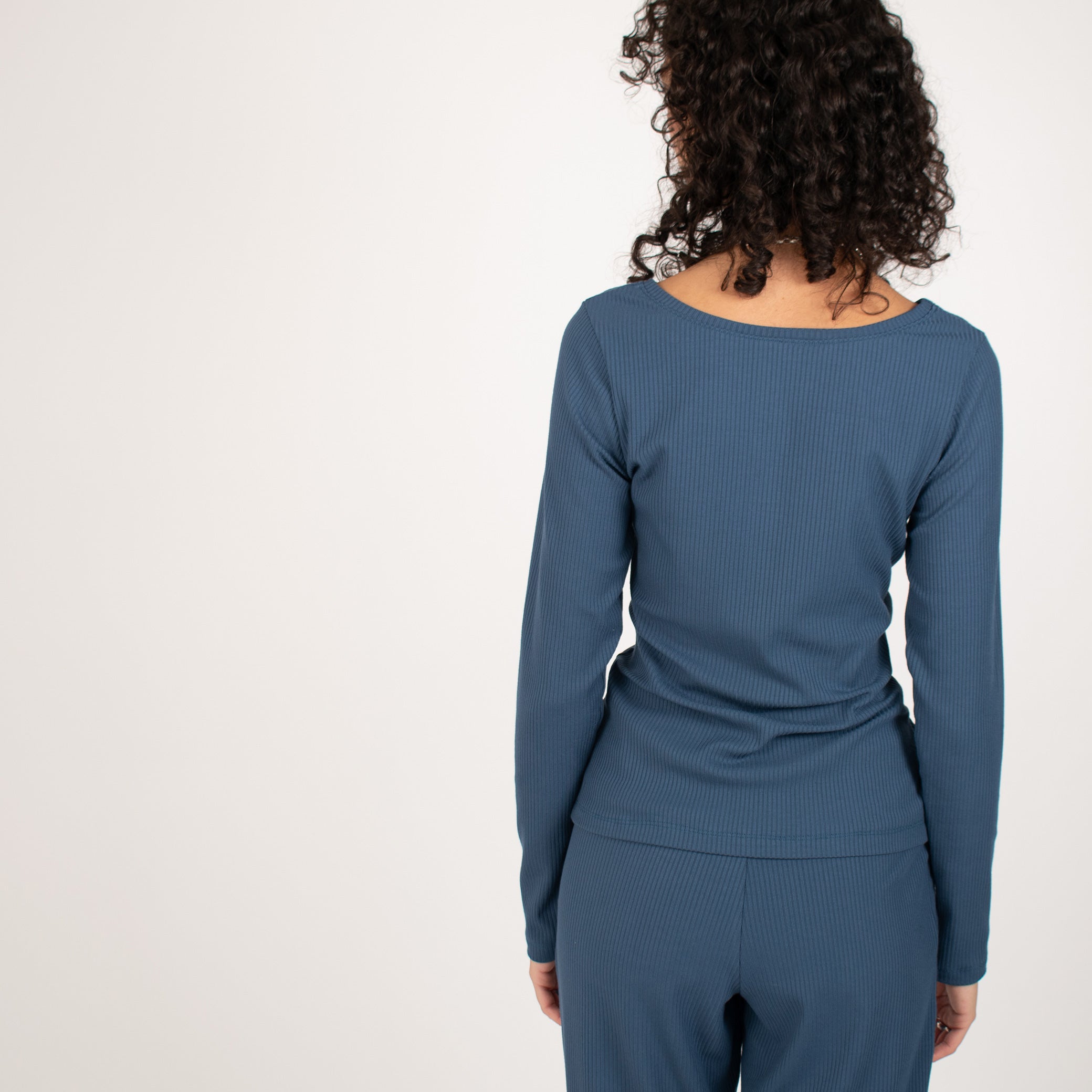 Woman wearing blue rib knit reversible long sleeve top with matching blue fitted sweatpants 